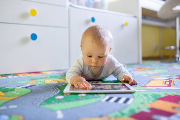 Portrait of cute little toddler child, playing on tablet, baby boy smiling Portrait of cute little toddler child, playing on tablet, baby boy smiling happily film screening stock pictures, royalty-free photos & images