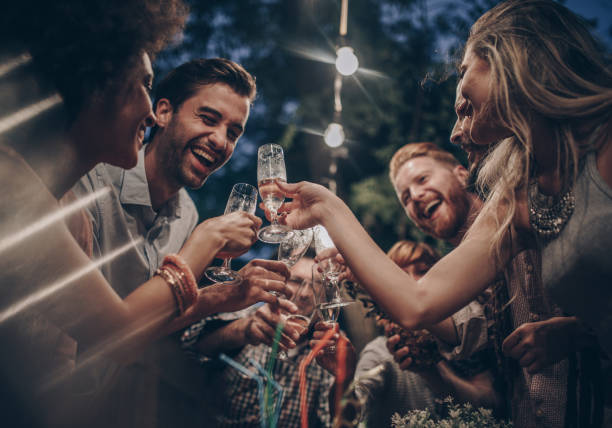 istock Large group of happy people having fun while toasting with alcohol on a night party. 956850312