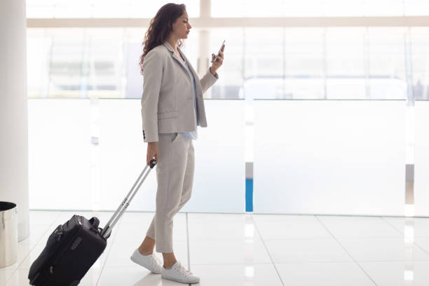istock Businesswoman pulling luggage and texting 956859900