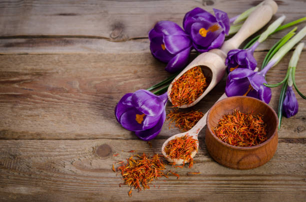 crocus flowers and spoon with soffron  on wooden table stock photo