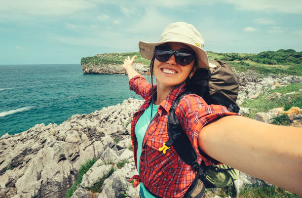 happy woman backpacker traveler take a selfie photo on amazing ocean coast - feriado fotos imagens e fotografias de stock