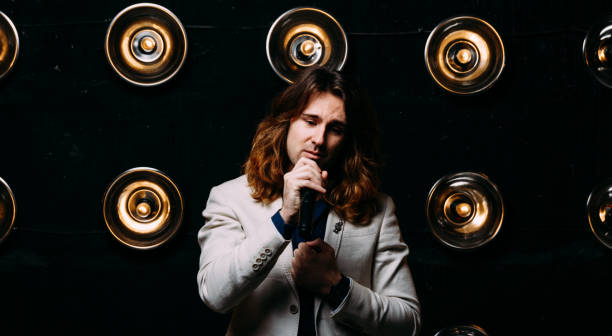 istock men singer with long hair, with microphone on the stage 956866020