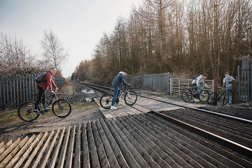 Teenage boys pushing their bikes across a railroad track crossing.