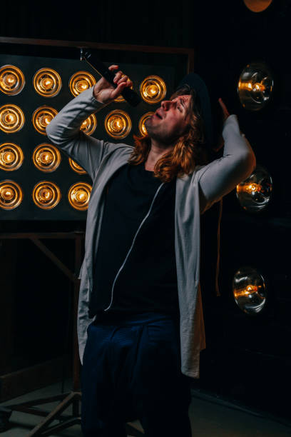 istock men singer with long hair, with microphone on the stage 956869918