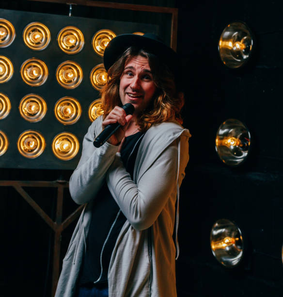 istock men singer with long hair, with microphone on the stage 956869944