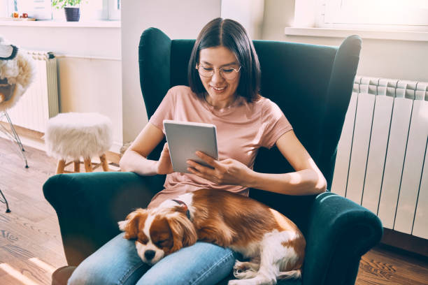 istock young asian woman sitting with her dog and using her tablet 956879018