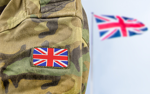 Military man posing in front of UK flag