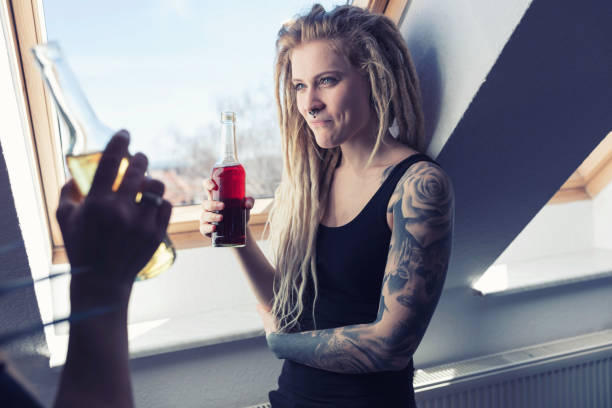 giovane donna tatuata che beve limonata con gli amici a casa - girlfriend blue eyes cheerful looking at camera foto e immagini stock