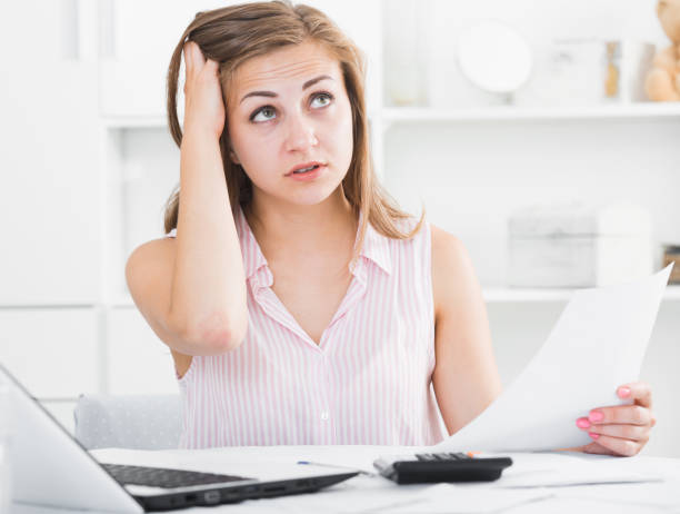 istock Young woman looking worriedly at bills 956888740