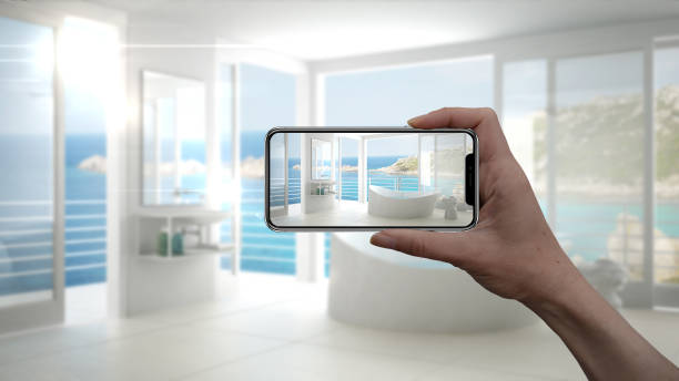 istock Hand holding smart phone, AR application, simulate furniture and interior design products in real home, architect designer concept, blur background, modern bathroom 956892184
