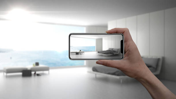 istock Hand holding smart phone, AR application, simulate furniture and interior design products in real home, architect designer concept, blur background, modern bedroom 956894418