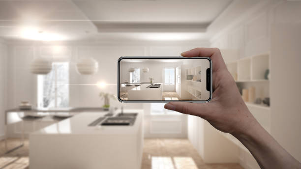 istock Hand holding smart phone, AR application, simulate furniture and interior design products in real home, architect designer concept, blur background, modern kitchen 956895372
