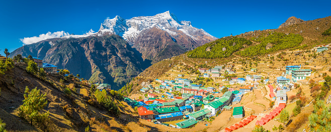 Panoramic view over the colourful teahouses and lodges of Namche Bazaar, the iconic Sherpa village and trading post nestled in a remote natural amphitheatre high in the Himalaya mountains of the Everest National Park, Nepal, a UNESCO World Heritage Site.