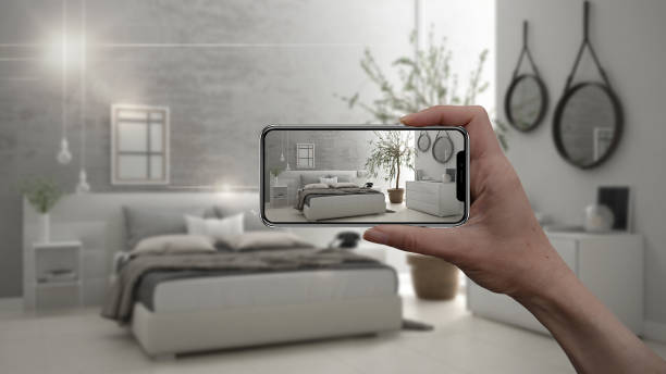istock Hand holding smart phone, AR application, simulate furniture and interior design products in real home, architect designer concept, blur background, modern bedroom 956896150