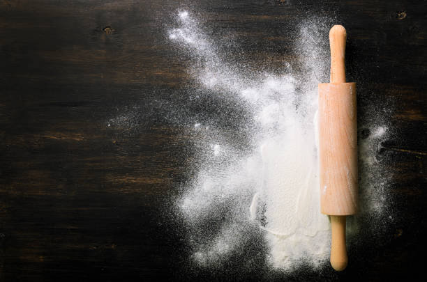 istock Baking background with free space for your text. Rolling pin and flour on black table. Copy space. Top view 956902094