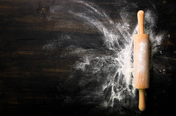 istock Baking background with free space for your text. Rolling pin and flour on black table. Copy space. Top view 956902254