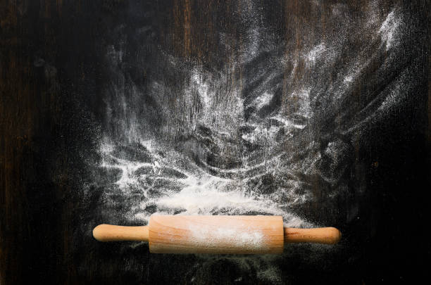 istock Baking background with free space for your text. Rolling pin and flour on black table. Copy space. Top view 956903234