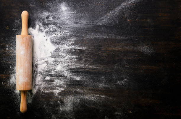 istock Baking background with free space for your text. Rolling pin and flour on black table. Copy space. Top view 956903334