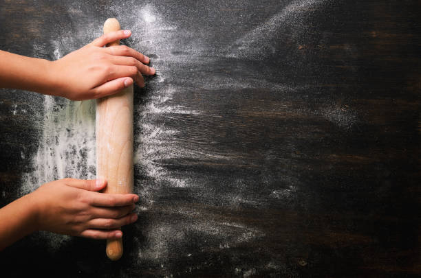 istock Girl hands keep rolling pin with flour on dark black table, baking background, top view, copy space for your text, meru, recipe. Banner 956903612