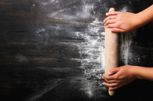 istock Girl hands keep rolling pin with flour on dark black table, baking background, top view, copy space for your text, meru, recipe. Banner 956905606