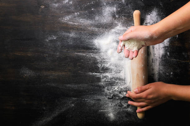istock Girl hands keep rolling pin with flour on dark black table, baking background, top view, copy space for your text, meru, recipe. Banner 956905640