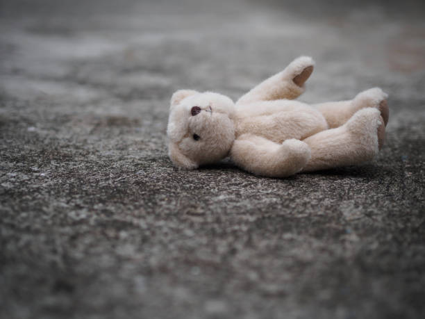 eddy bear is laying down on the floor. lonely concept. international missing children's day. Teddy bear is laying down on the floor. lonely concept. international missing children's day. behavior teddy bear doll old stock pictures, royalty-free photos & images