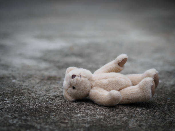 istock Teddy bear is laying down on the floor. lonely concept. international missing children's day. 956906136