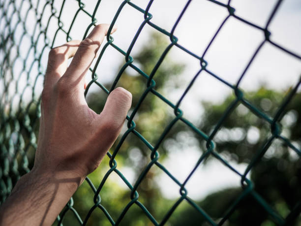 istock Man hand holding on chain link fence to remember Human Rights Day concept. 956906878