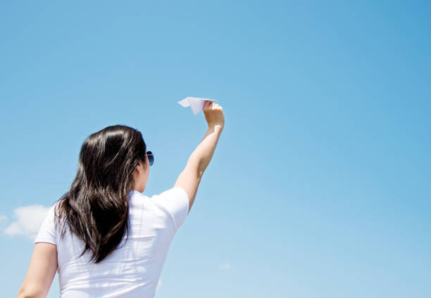 istock Woman throwing a paper airplane 956906990