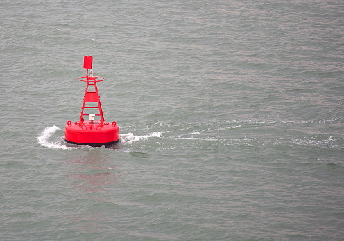 Red, or port, channel marker buoy at edge of main channel with incoming tide, Klang River, Malaysia