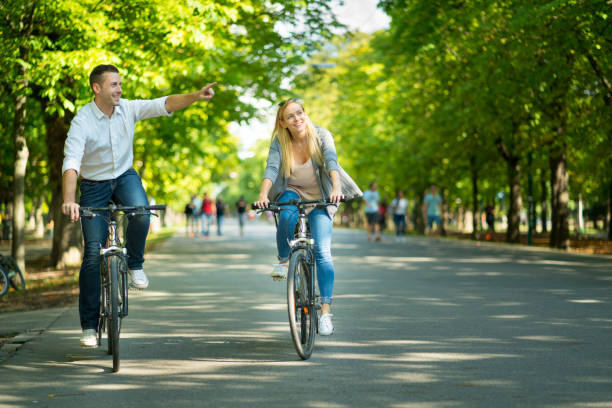 casual happy young tourist couple cycling through alley - prater park imagens e fotografias de stock