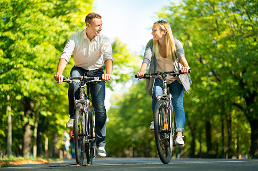 happy smiling young couple on bikes in spring looking at each other