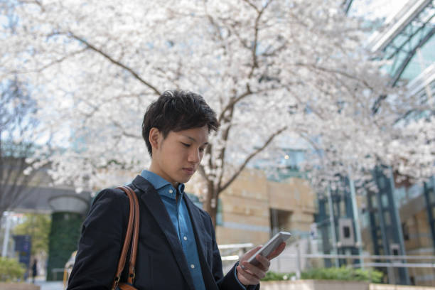 istock Young businessman waiting under cherry blossoms 956911812