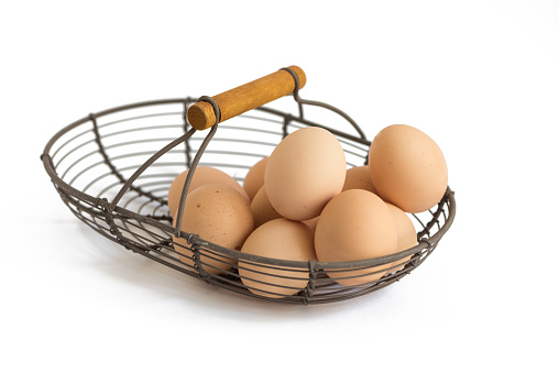 Organic eggs in  provence rustic wire basket on white background