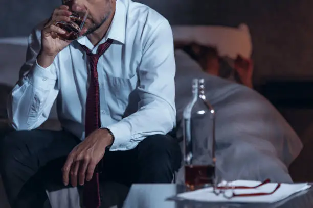 Man drinking whiskey in a suit while his woman is asleep