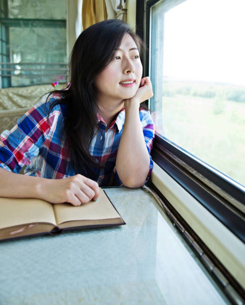 istock Young asian woman reading book on a train 956925292