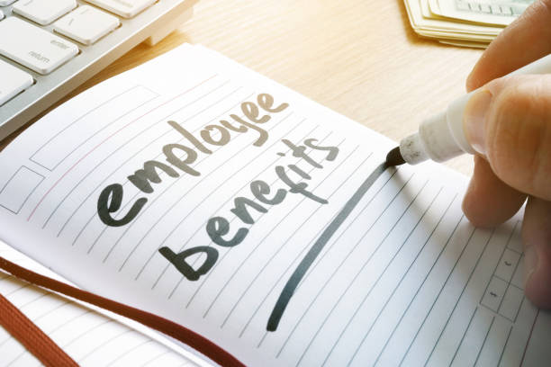 istock Hand is writing Employee benefits in a note. 956925420