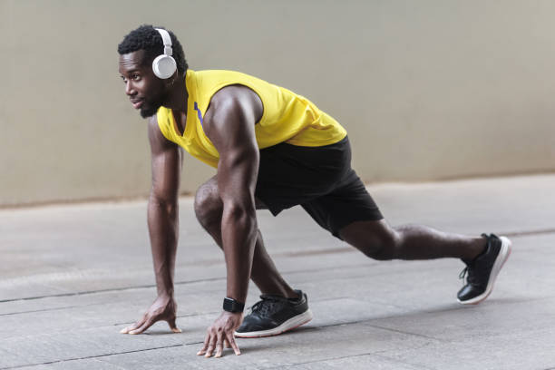 istock Profile view. African athlete man in running start pose 956925642