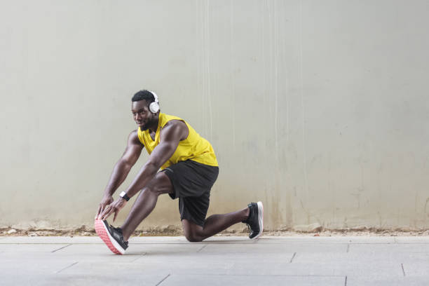 istock Afro runner in yellow sportswear stretching before doing morning workout 956925972