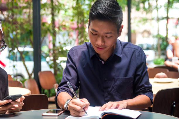 istock Malaysia college student writing down notes in local cafe 956931696