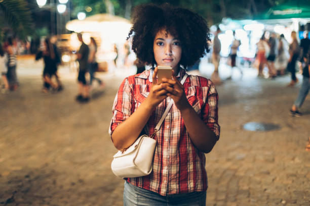 istock Woman walking and using smart phone on street 956932028