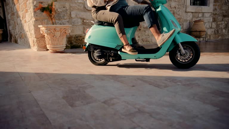 Young tourist friends riding vintage scooter in old European city