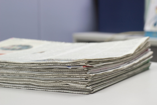Closeup - Newspaper Stack on white table in office