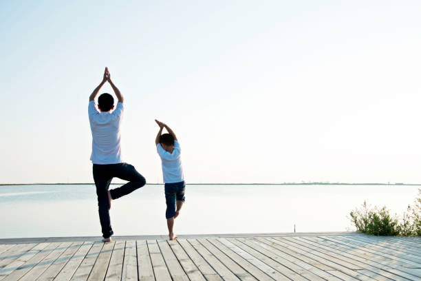 istock Father with his son doing yoga by the lake 956955126