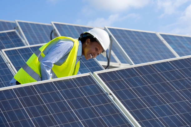 femme d’ingénieur énergie travaillant sur un toit avec panneaux solaires. - solar grid photos et images de collection