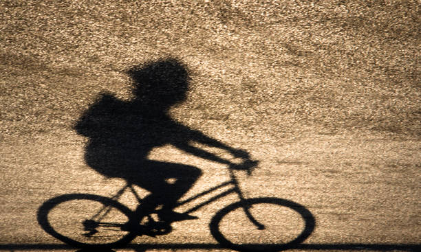 silhouette défocalisé ombre floue d’un adolescent, faire du vélo - shadow focus on shadow women sunset photos et images de collection