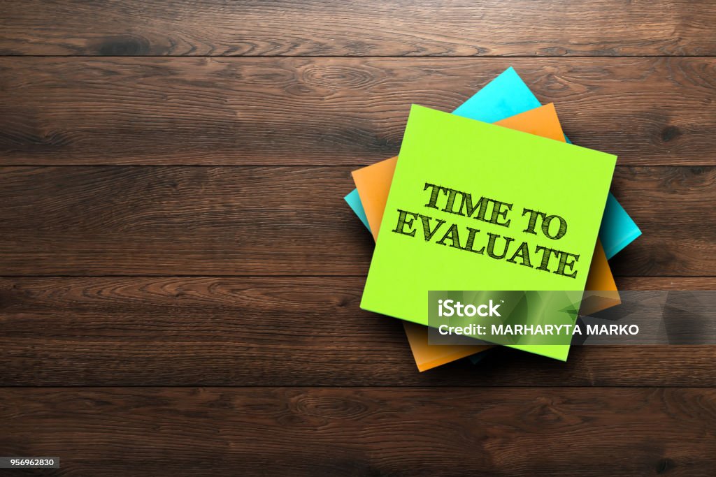 Time To Evaluate, the phrase is written on multi-colored stickers, on a brown wooden background. Business concept, strategy, plan, planning. Comparison Stock Photo