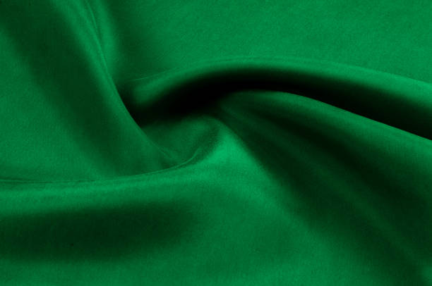 istock Background texture, pattern. Thick thick silk fabric is green. This satin fabric is ideal for creating a smooth flow in design, it has a liquid drape and exquisite shine. 956968438
