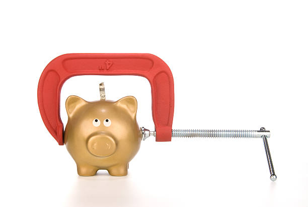 istock C-clamp squeezing golden piggy bank 95697009