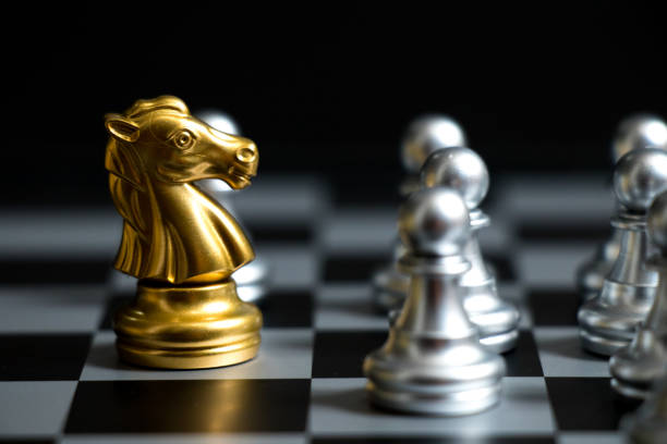 istock Gold horse in chess game face with the another silver team on black background (Concept for company strategy, business victory or decision) 956976476